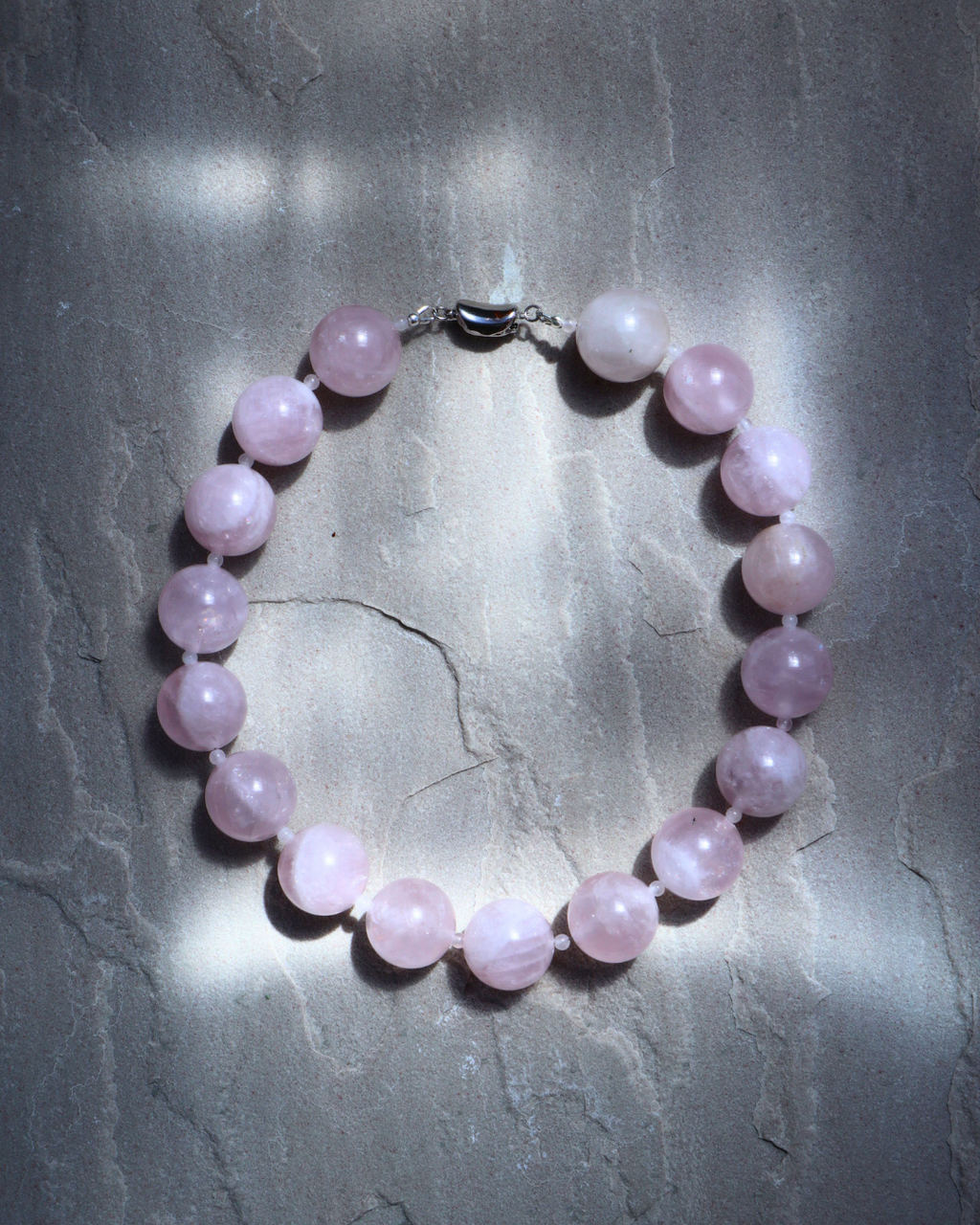 Pink beaded bracelet on a textured gray surface